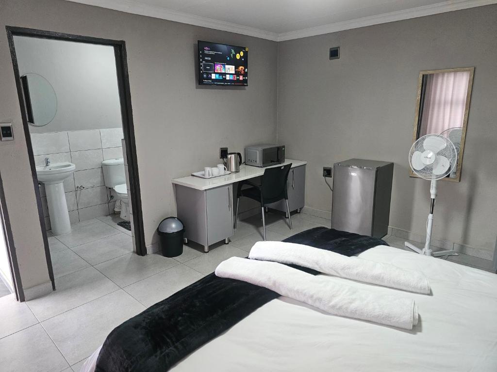 a bedroom with a bed and a desk and a bathroom at Vation Nation Guest House in Mokopane