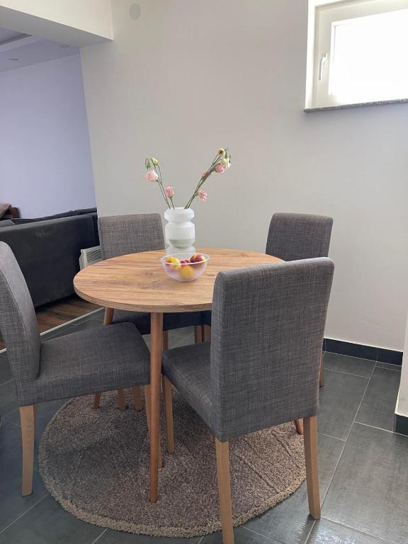 a wooden table with chairs and a bowl of fruit on it at Kocić apartmani in Pojate
