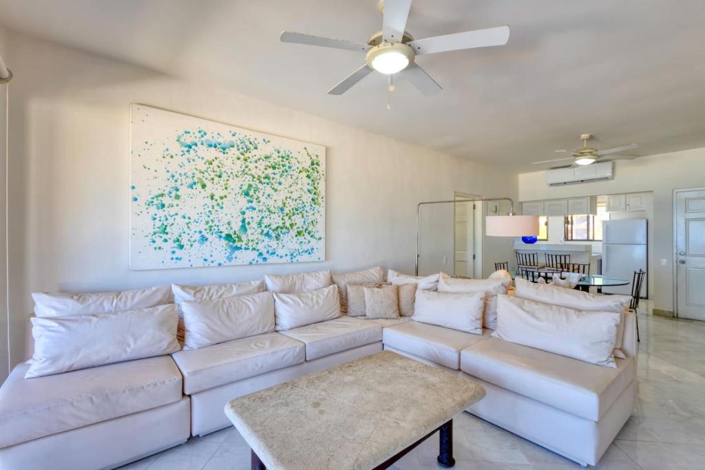 a living room with a white couch and a painting at Beachfront Condo at Casa del Mar in El Bedito