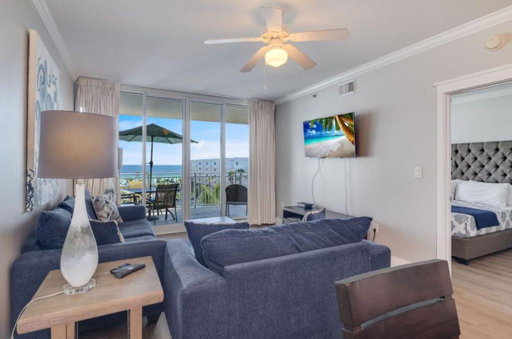 - un salon avec un canapé bleu et un lit dans l'établissement NEW Beachfront Bliss- Sleeps 8, 2 Pools, Lazy River, à Fort Walton Beach
