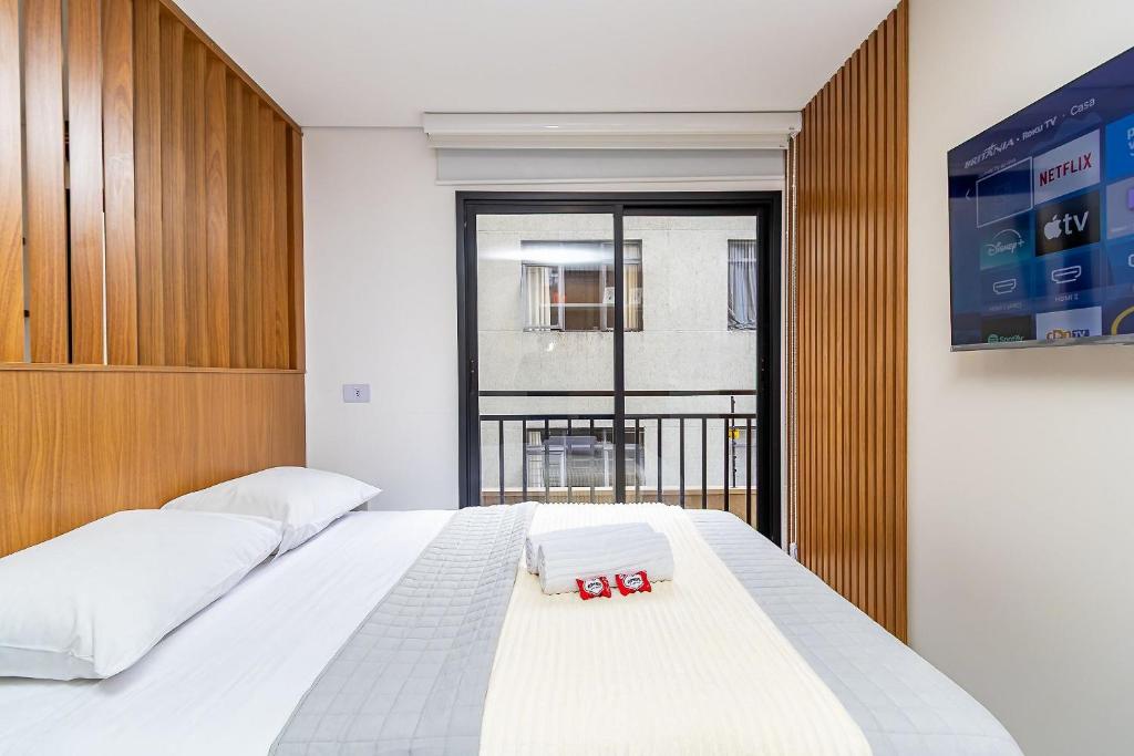 a bedroom with two beds and a large window at Studio Completo ao Lado da PUC - CAP109 in Curitiba