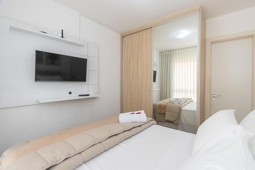 een witte kamer met een bed en een tv aan de muur bij Apartamento de 1 Quarto com Sofa-Cama - CEN1104 in Curitiba