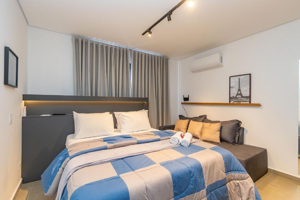 a bedroom with a large bed with blue and white sheets at Estúdio Completo para 4 Pessoas no Eixo - EIX0201 in Curitiba