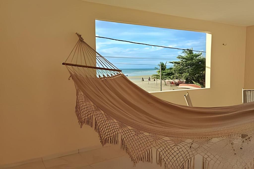 a hammock in a room with a view of the beach at Eficiência - Casa São Pedro - Casa Beira Mar in Camocim