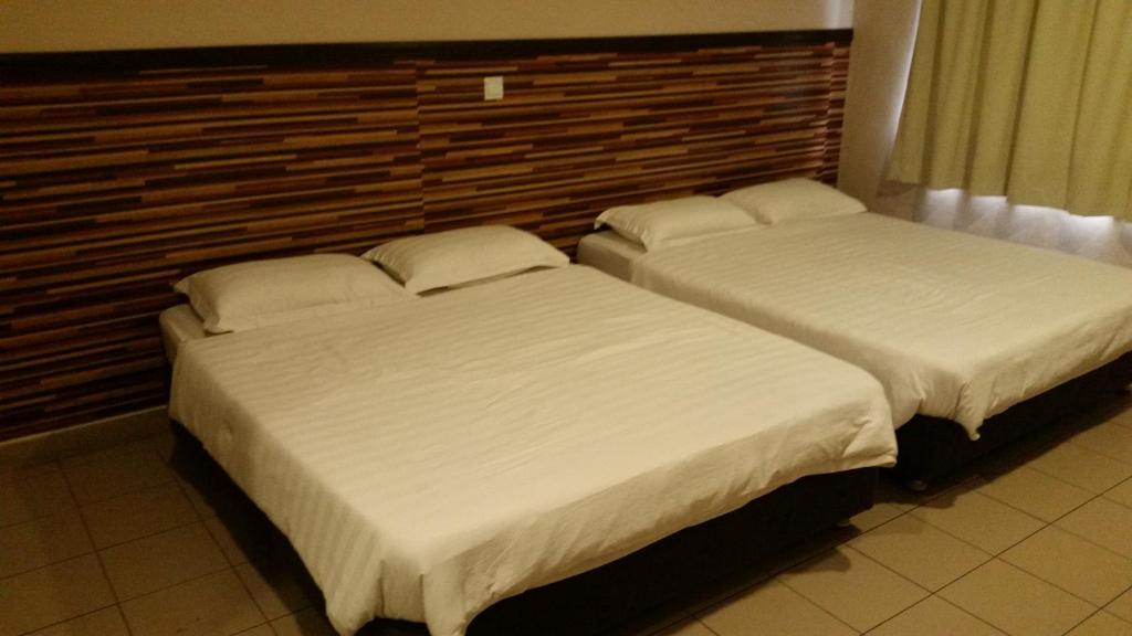 dos camas sentadas una al lado de la otra en un dormitorio en Hotel Iskandar en Kota Kinabalu