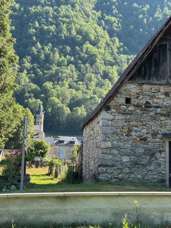 an old stone building with a church in the background at Pyrenees family T3 in Aulus-les-Bains