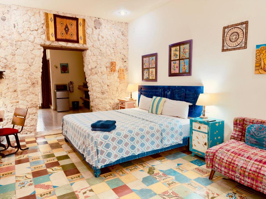 a bedroom with a blue bed and a couch at Casa Chaak Maya - Estudio privado con alberca en Mérida in Mérida