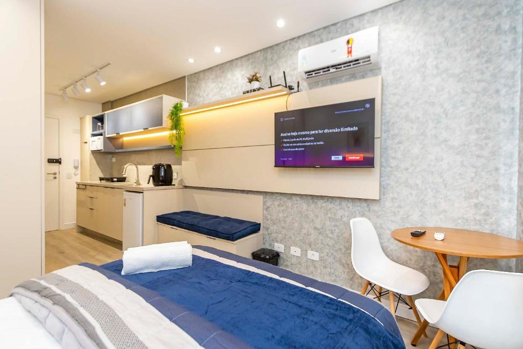 a bedroom with a bed with a tv on the wall at Studio Completo para 3 pessoas com A/C - EIX0302 in Curitiba