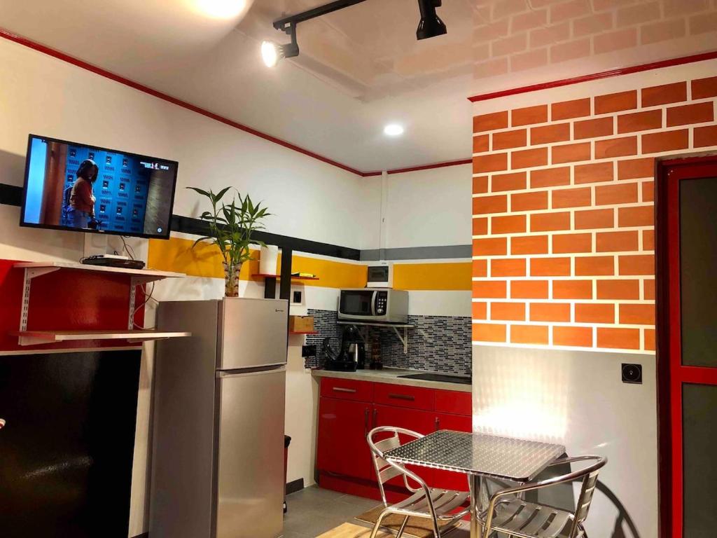 a kitchen with a refrigerator and a table and a tv at Studio king-size bed, all comfort in Balaté in Saint-Laurent du Maroni