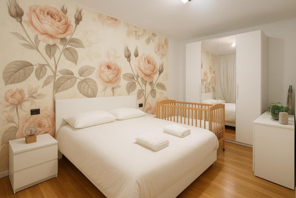 a bedroom with a white bed with flowers on the wall at Apt Matteucci 18 centro storico con parcheggio privato in Ravenna
