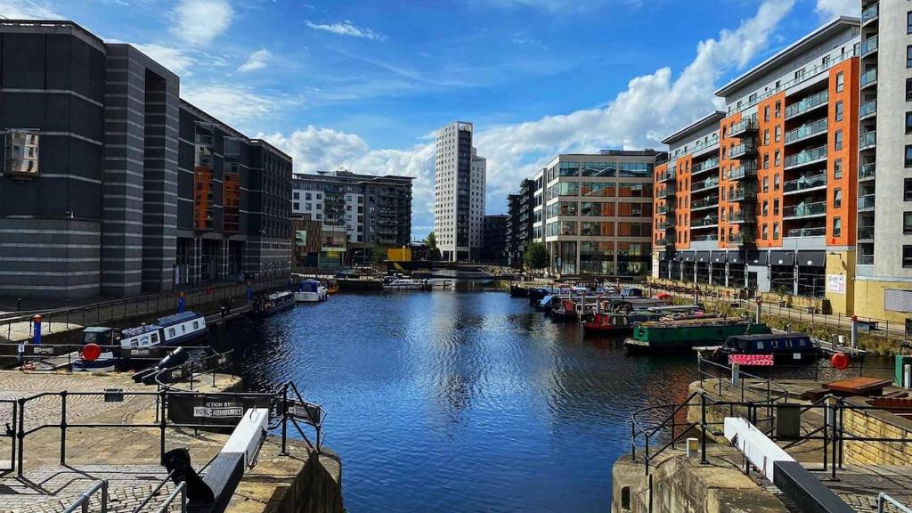 a river with boats in a city with buildings at Leeds Dock Apartment in Hunslet