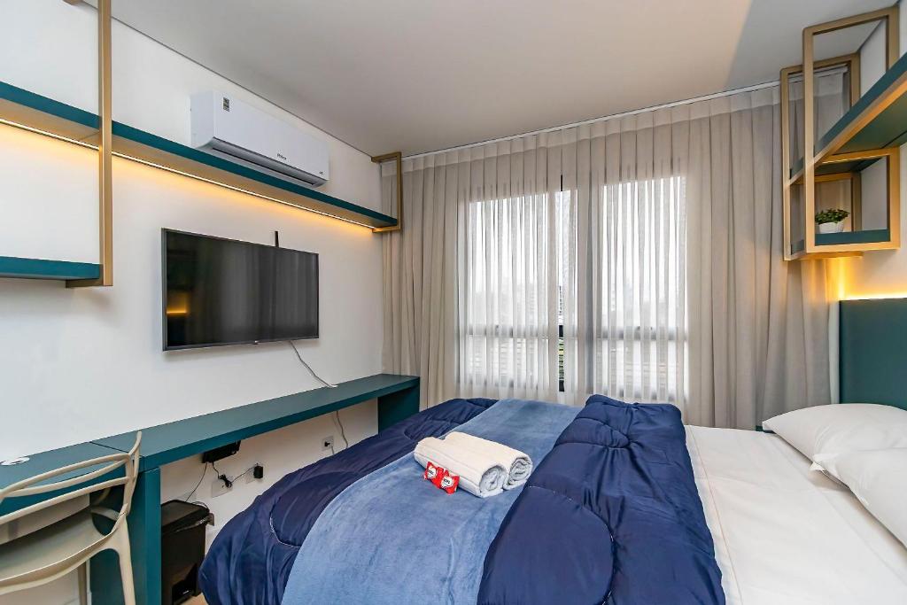a bedroom with a blue bed with a tv on it at Studio Completo em Região Tranquila - EIX0502 in Curitiba