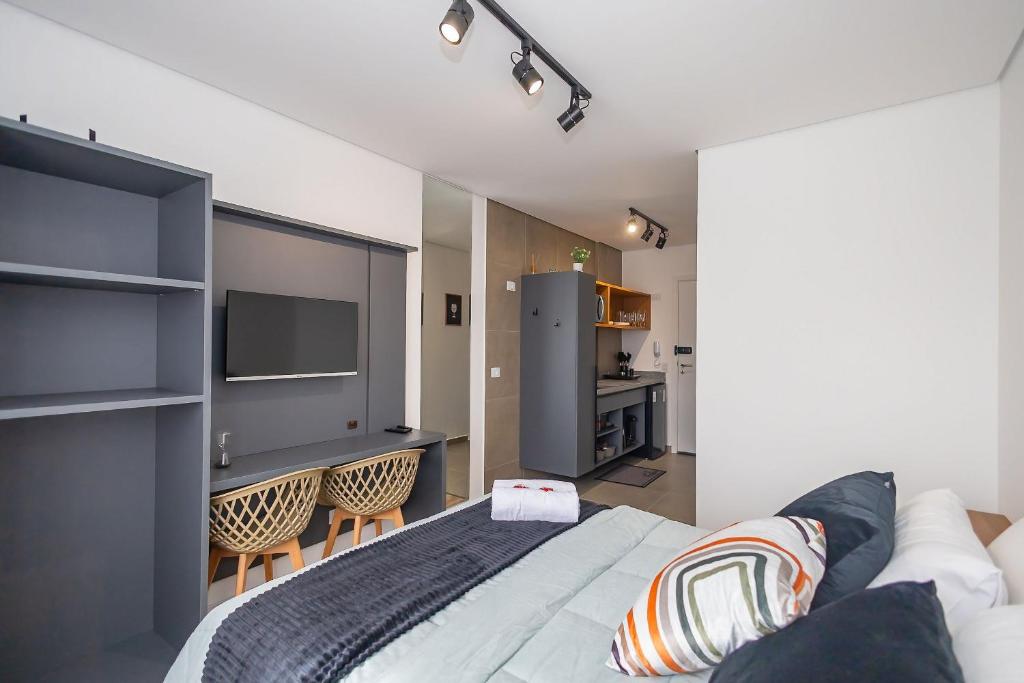 ein Schlafzimmer mit einem Bett und eine Küche mit einem Kühlschrank in der Unterkunft Studio Completo no Eixo - EIX0507 in Curitiba