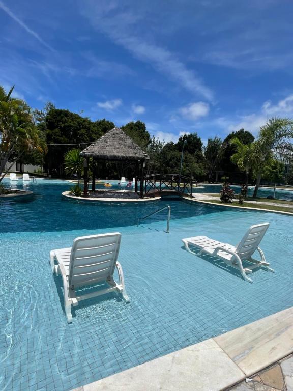 zwei Stühle und ein Pavillon in einem Schwimmbecken in der Unterkunft Apartamento no resort in Barra de São Miguel