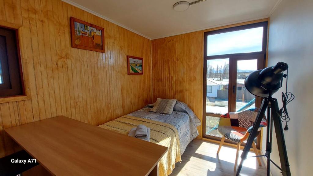 a bedroom with a bed and a table and a camera at CABAÑA EL BUHO - ESMERALDA in Puerto Natales