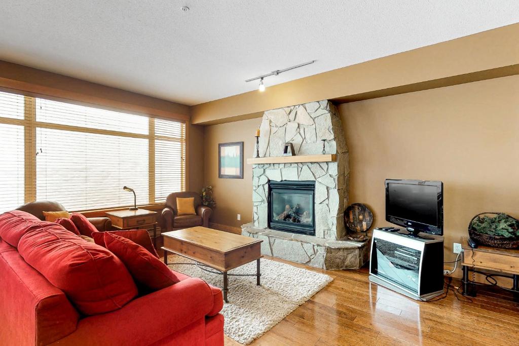 a living room with a red couch and a fireplace at Glacier Lodge 106 in Big White