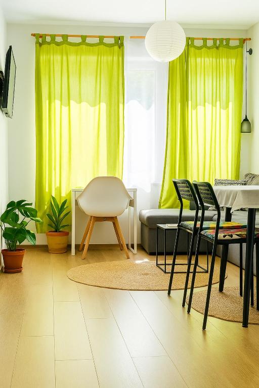 a living room with green curtains and a table and chairs at Chill Breeze Apartment in Stara Zagora