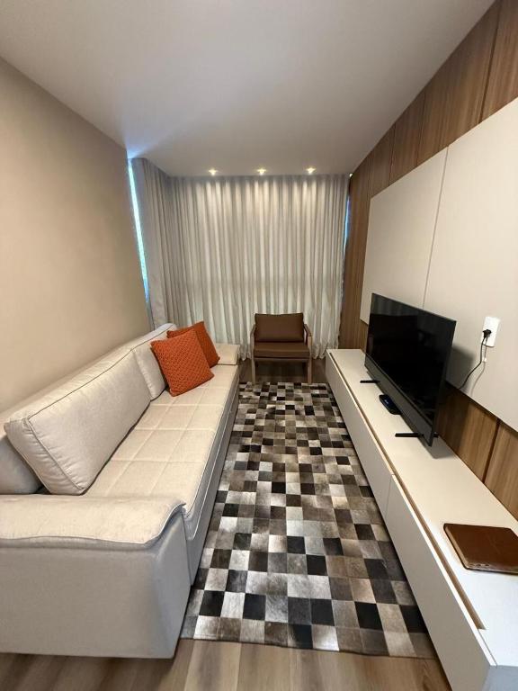 a living room with a white couch and a tv at Apartamento Premium Lazer Completo, Rooftop e Academia in Belém