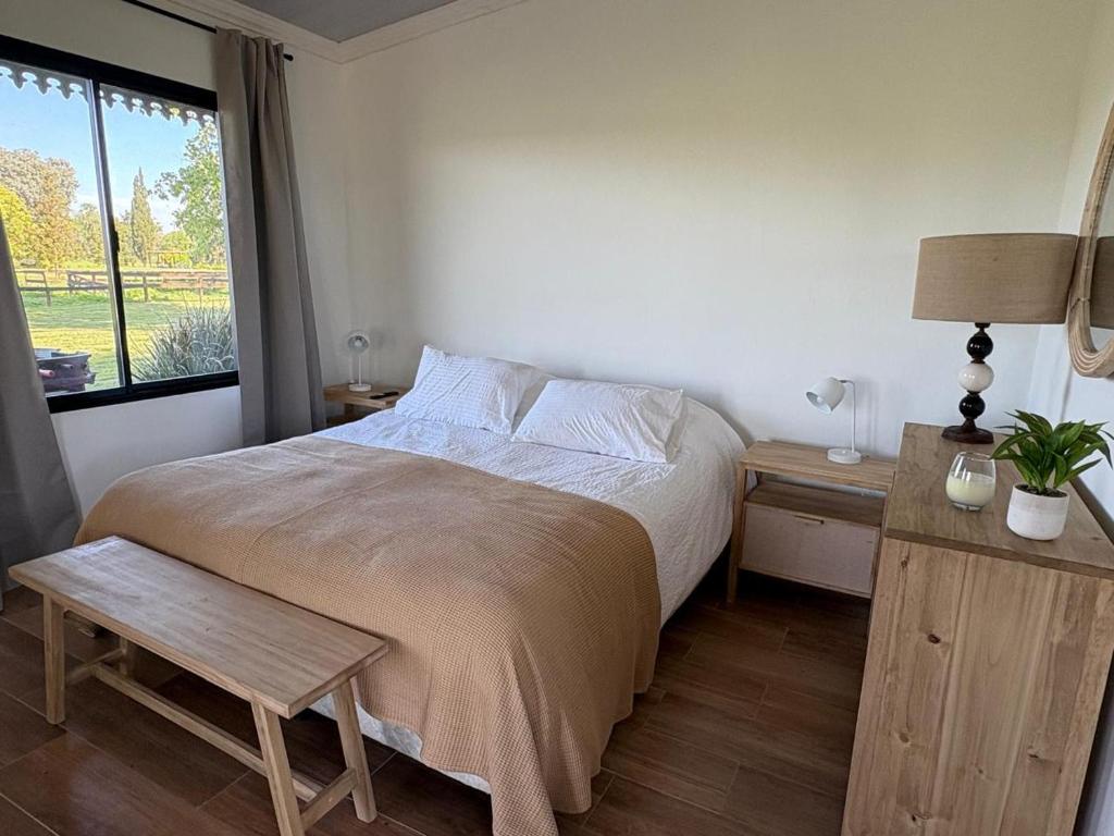 a bedroom with a bed with a table and a window at Aires de Capilla in Capilla del Señor