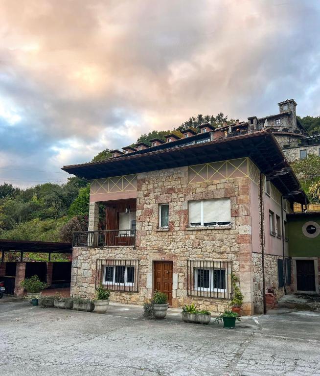 a large brick building with windows and a balcony at Apartamentos y Pensión El Campanu in Cangas de Onís
