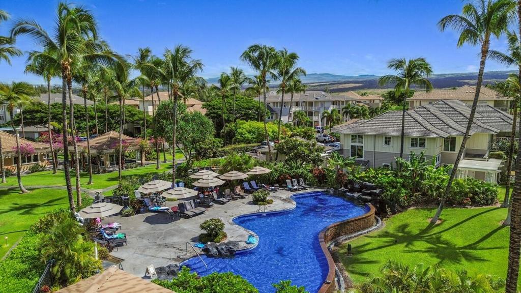 Una vista aérea de la piscina de un resort con sombrillas. en Hale Kaileia Kai - Peaceful Ground Floor Getaway, en Waikoloa