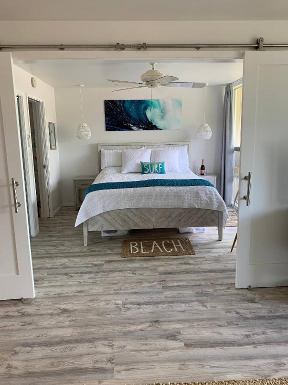a bedroom with a bed and a beach sign on the floor at Chic Maui Condo Steps From Beach & Ocean in Wailea