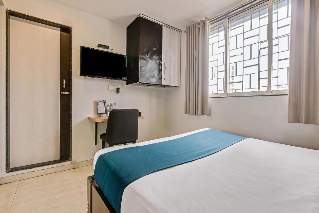 a hotel room with a bed and a chair in it at Hotel O Nirsukh Palace in Navi Mumbai