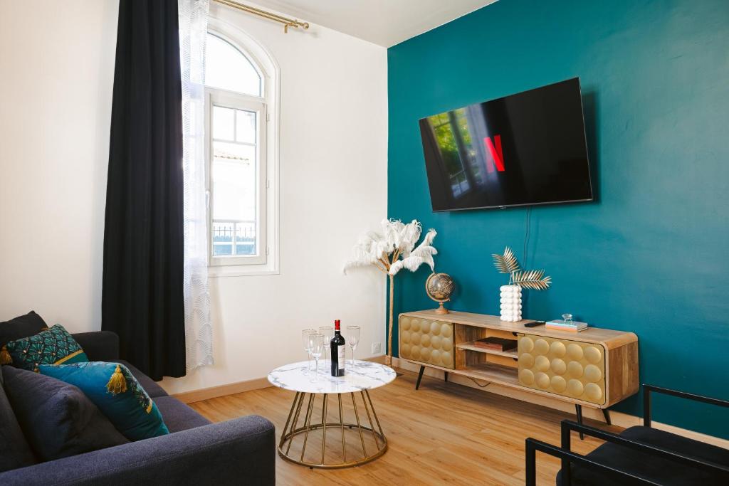 a living room with a couch and a tv on a blue wall at Gatsby - Appartement rénové élégant, Hypercentre Saintes, Calme, Fibre, TV 4K, Netflix in Saintes