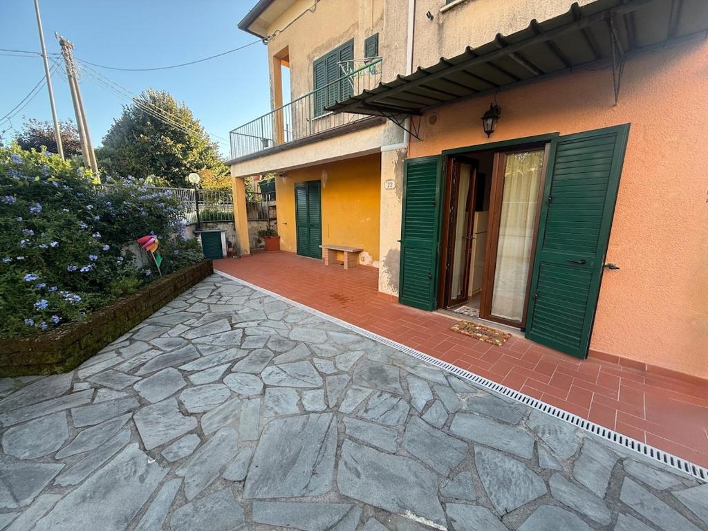 a house with green doors and a stone patio at Emily house in Casa Gherardi