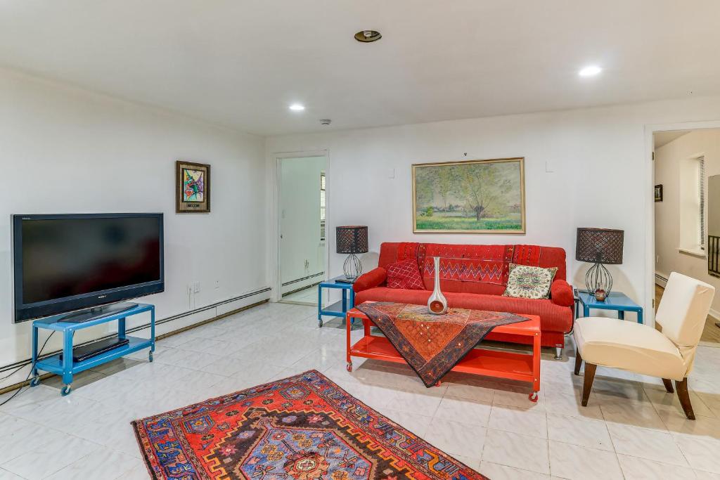 a living room with a red couch and a tv at Easy NYC Commute Guttenberg Getaway Near Parks in Guttenberg