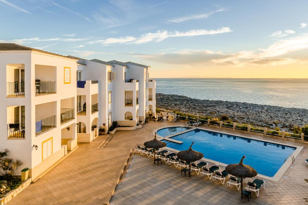 a view of a hotel with a swimming pool and the ocean at Apartamentos Blancala in Cala Blanca