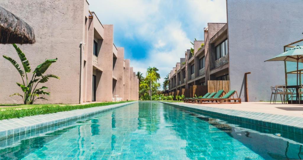 une piscine devant un bâtiment dans l'établissement Apê Praia do Toque com Ar no Quarto e Sala, Condomínio com Academia, Quadra de Beach Tennis e Vôlei, Estacionamento Grátis e Restaurante, à São Miguel dos Milagres