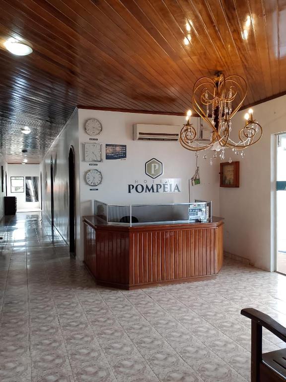 a lobby with a reception desk and a chandelier at Hotel Pompéia em Almeirim in Almeirim