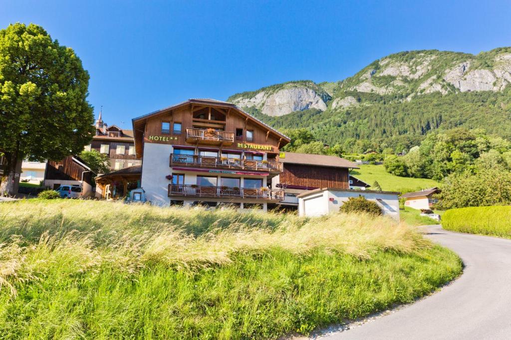 a building on a hill next to a road at Accueil Savoyard in Mieussy