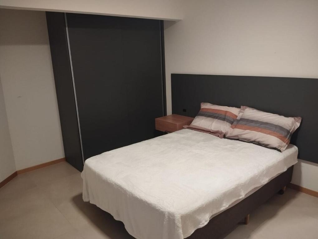 a bedroom with a white bed with a black headboard at Apartment in the center 500 meters from Proeb in Blumenau