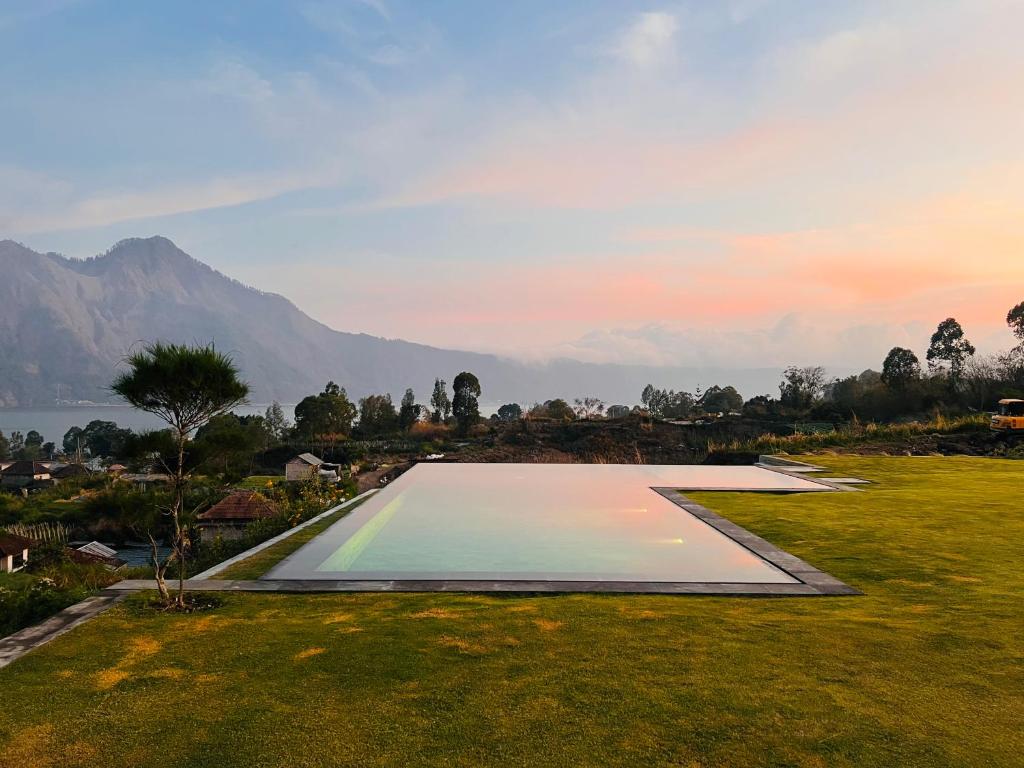 a swimming pool in a field with a mountain in the background at The Kamsha Kintamani in Kubupenlokan