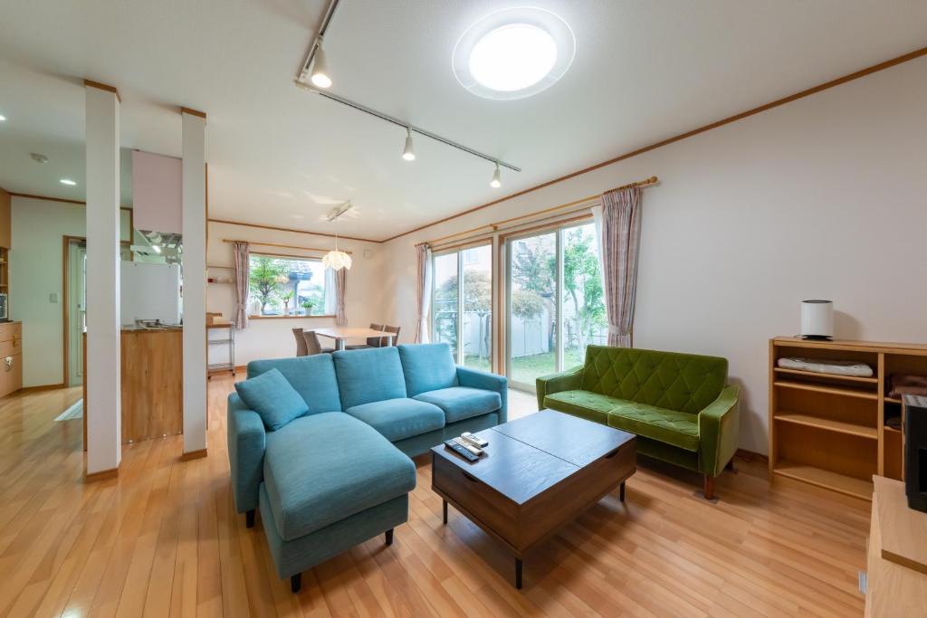 a living room with a blue couch and two green chairs at GuestHouse　YOU&I in Fujikawaguchiko
