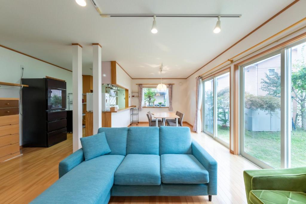 a large blue couch in a living room with windows at GuestHouse　YOU&I in Fujikawaguchiko