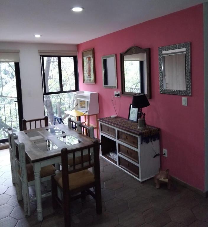 a dining room with a table and chairs and a pink wall at Amplio, equipado con vistas a jardín en el corazón CDMX in Mexico City