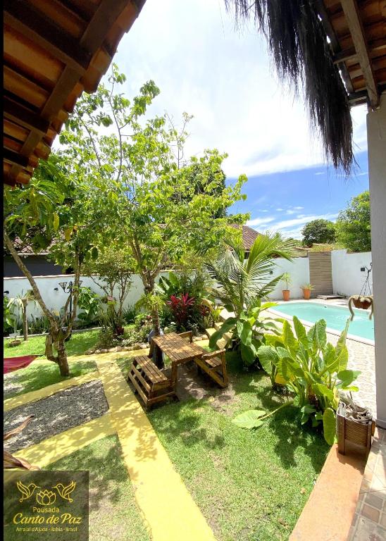 a garden with a picnic table and a pool at Pousada Canto de Paz in Arraial d'Ajuda