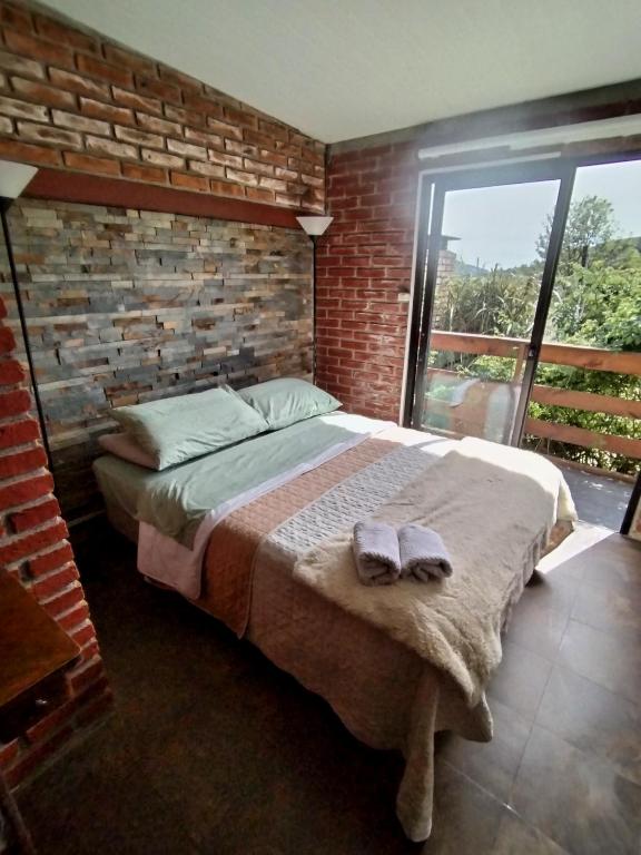 une chambre avec un grand lit avec un mur de briques dans l'établissement Vinoteca Vintage, à Piriápolis