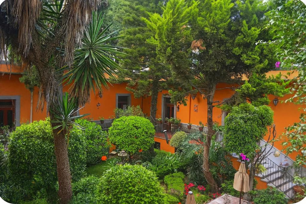 an orange building with trees and plants in front of it at Hacienda Gobernadores Boutique Stay in a Historic 19th-Century Hacienda in Mexico City