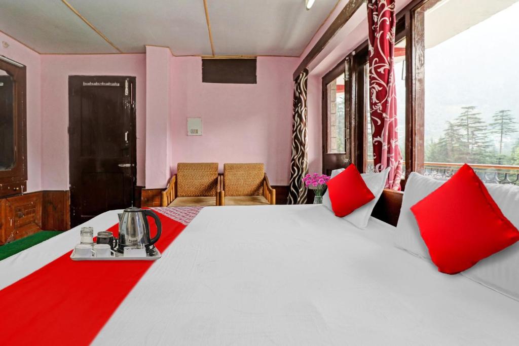 una camera da letto con un grande letto bianco con cuscini rossi di Hotel O Hema Holiday Home a Manāli