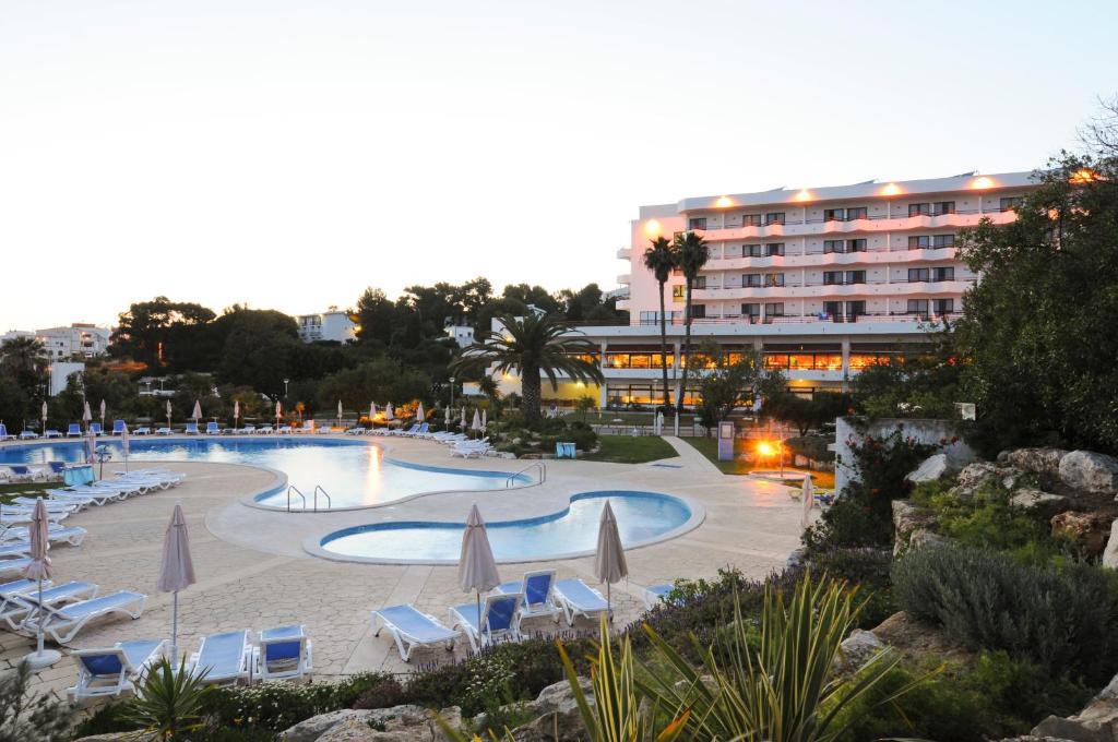 a large swimming pool with umbrellas and chairs and a hotel at INATEL Albufeira in Albufeira