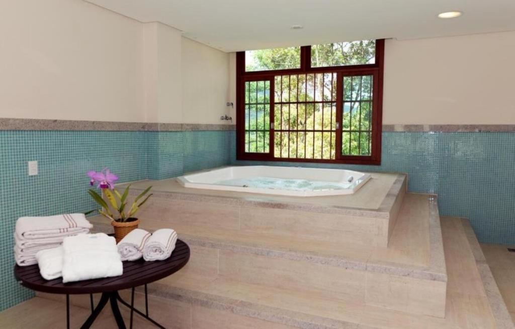 a bathroom with a tub and a table with towels at Apartamento com varanda e vista da Pedra Azul in Domingos Martins