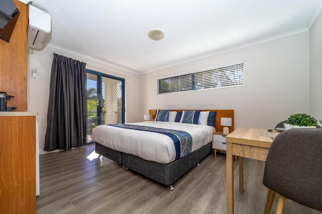 a bedroom with a bed and a desk and a table sidx sidx sidx at Spacious Mantra Hotel Room in Urangan