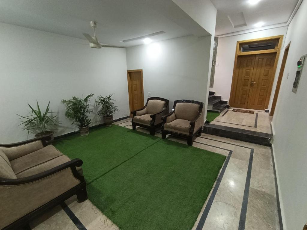 a living room with chairs and a green carpet at RMT Residencia entire apartment in Peshawar