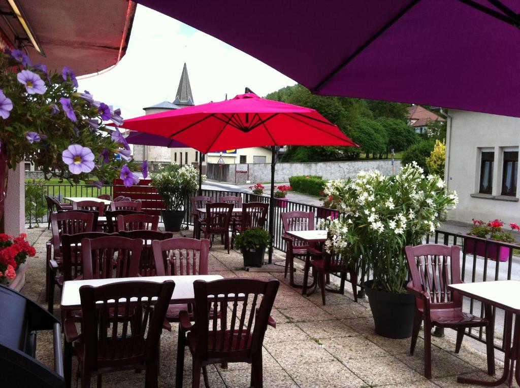 een groep tafels en stoelen met rode parasols bij Les Jolis Coeurs in Thiéfosse