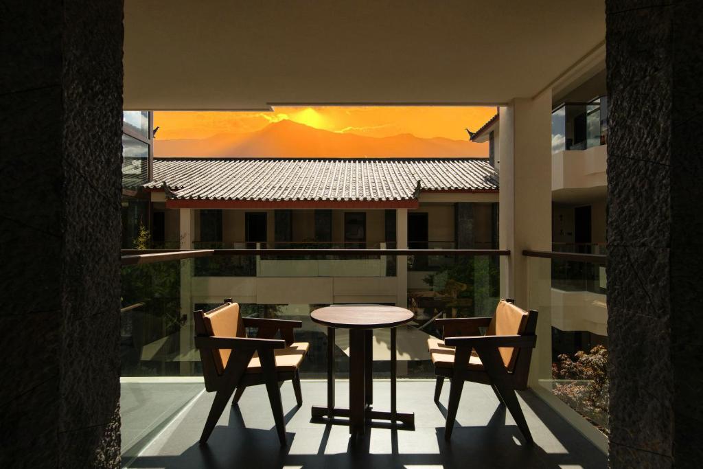een terras met een tafel en stoelen op een balkon bij The Mountain-View Terrace Hotel ,Coffee and Tea Villa at The Big Waterwheel,A luxury hotel featuring private terraces for snow mountain views, Western & Chinese breakfast, afternoon tea, English speaking service, and ticket reservation service in Lijiang