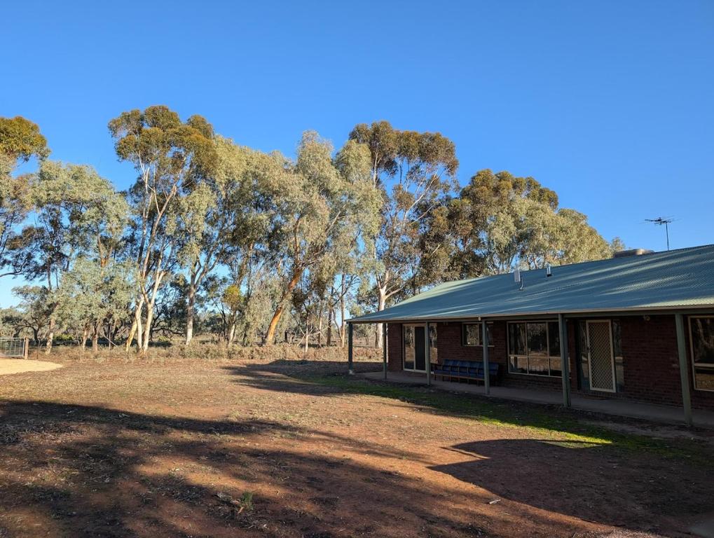 un bâtiment en briques rouges avec des arbres en arrière-plan dans l'établissement Willa Villa Bush Retreat - Gol Gol, à Gol Gol
